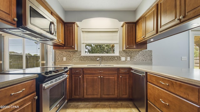 kitchen featuring decorative backsplash, stainless steel appliances, a sink, and light countertops