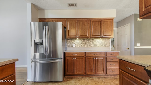 kitchen featuring decorative backsplash, light countertops, visible vents, and stainless steel fridge with ice dispenser