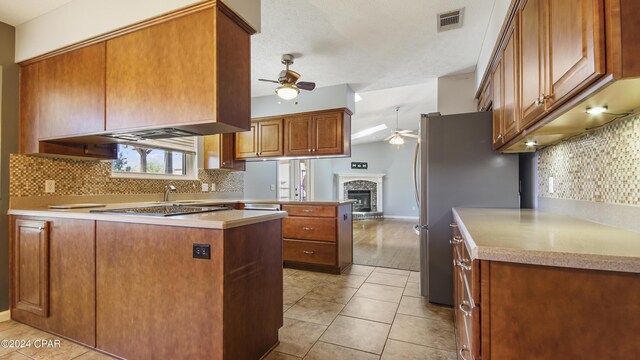 kitchen featuring ceiling fan, light tile patterned floors, a peninsula, visible vents, and freestanding refrigerator