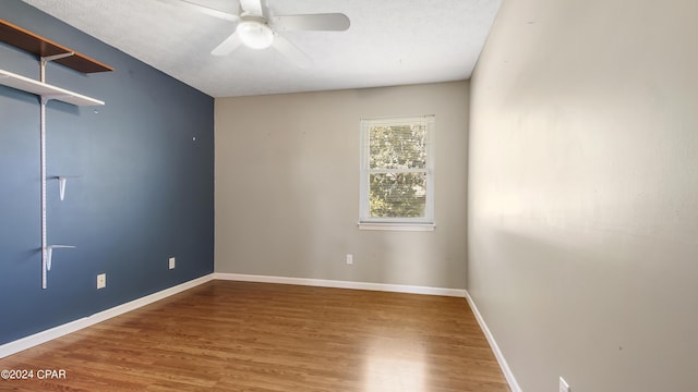 unfurnished room with ceiling fan, a textured ceiling, wood finished floors, and baseboards