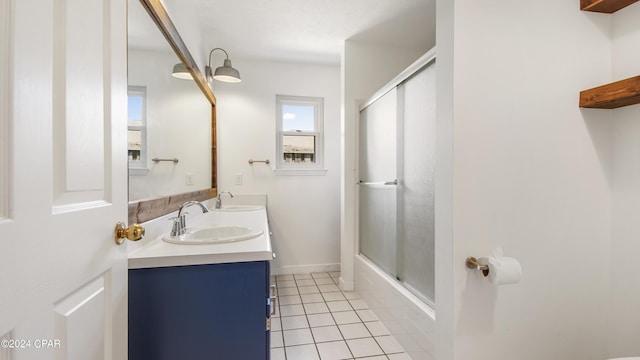 full bath featuring double vanity, shower / bath combination with glass door, tile patterned flooring, and a sink