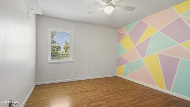 spare room featuring ceiling fan, baseboards, and wood finished floors