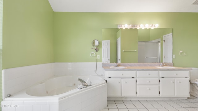 bathroom with double vanity, a jetted tub, a sink, and tile patterned floors