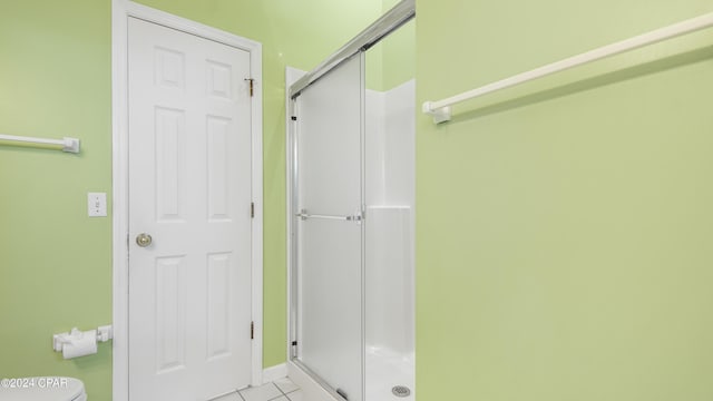 bathroom with a shower stall, toilet, and tile patterned floors