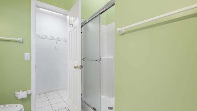 bathroom with a stall shower, toilet, and tile patterned floors