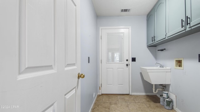 clothes washing area with light tile patterned floors, hookup for a washing machine, visible vents, cabinet space, and baseboards