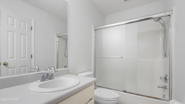 bathroom with combined bath / shower with glass door, vanity, and toilet