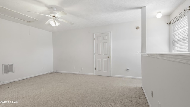 empty room featuring visible vents, attic access, a ceiling fan, carpet flooring, and baseboards