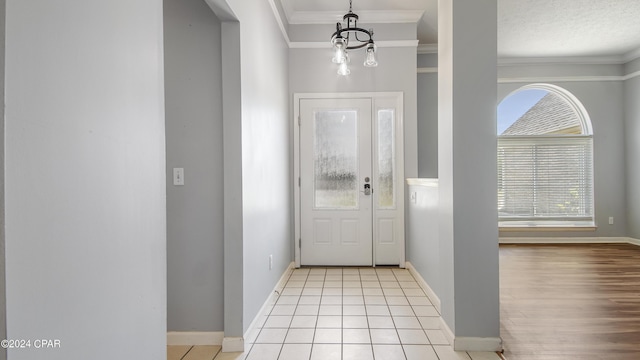 entrance foyer featuring ornamental molding, an inviting chandelier, baseboards, and light tile patterned floors