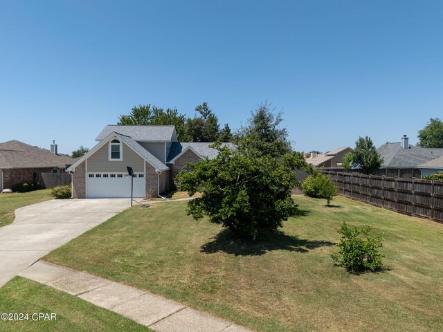 view of front of house with brick siding, concrete driveway, a front yard, fence, and a garage