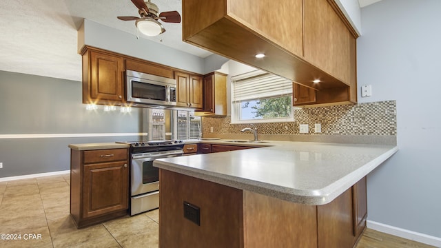 kitchen featuring a peninsula, backsplash, stainless steel appliances, and a sink