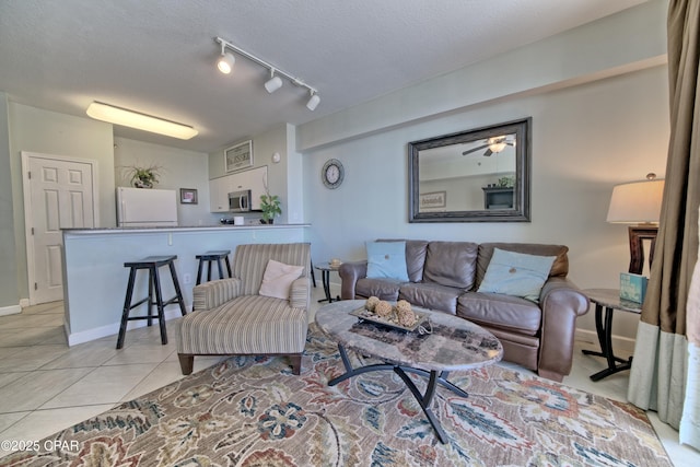 living room featuring track lighting, light tile patterned floors, baseboards, and a textured ceiling