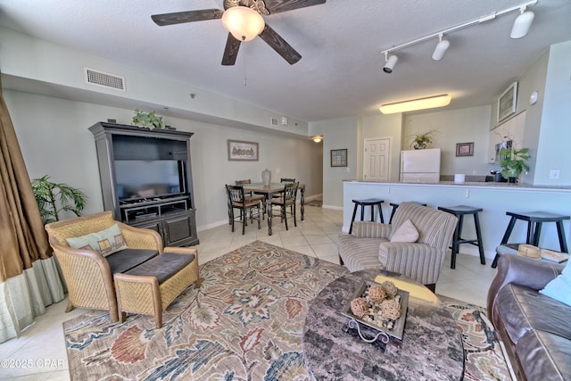 living room with visible vents, light tile patterned flooring, ceiling fan, rail lighting, and a textured ceiling