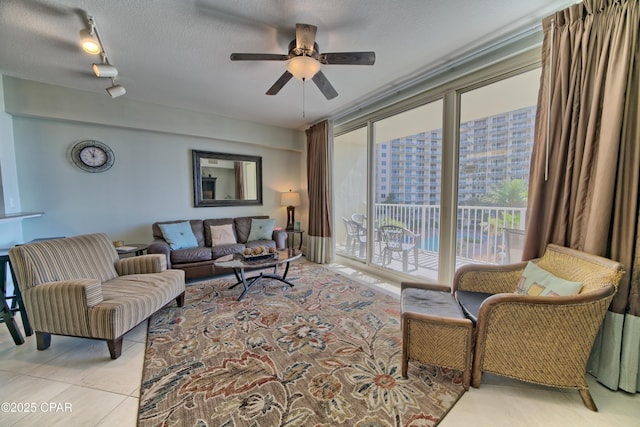 living area with a textured ceiling, light tile patterned flooring, and ceiling fan