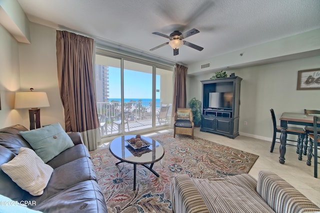 living area with visible vents, baseboards, ceiling fan, tile patterned floors, and a textured ceiling