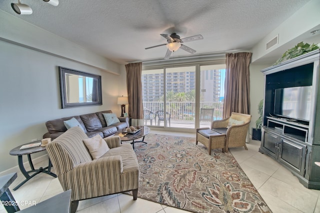living room with visible vents, a textured ceiling, ceiling fan, and light tile patterned flooring