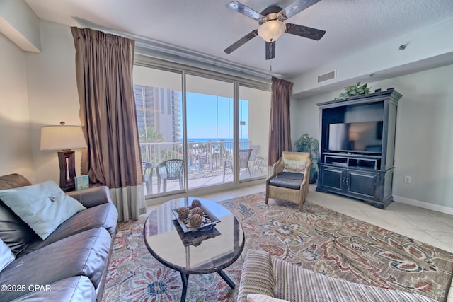 tiled living room with visible vents, baseboards, a textured ceiling, and a ceiling fan