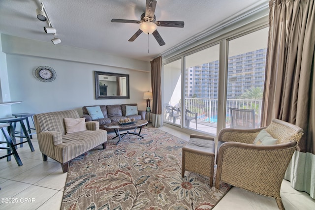 living room with rail lighting, light tile patterned flooring, a ceiling fan, and a textured ceiling