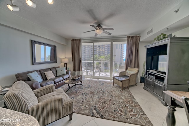 living area with light tile patterned floors, visible vents, a textured ceiling, and ceiling fan