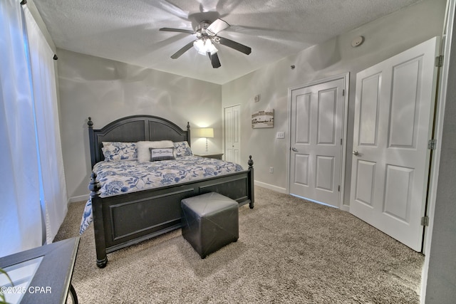 carpeted bedroom with a textured ceiling, baseboards, and a ceiling fan