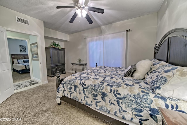 bedroom featuring visible vents, a textured ceiling, carpet flooring, baseboards, and ceiling fan