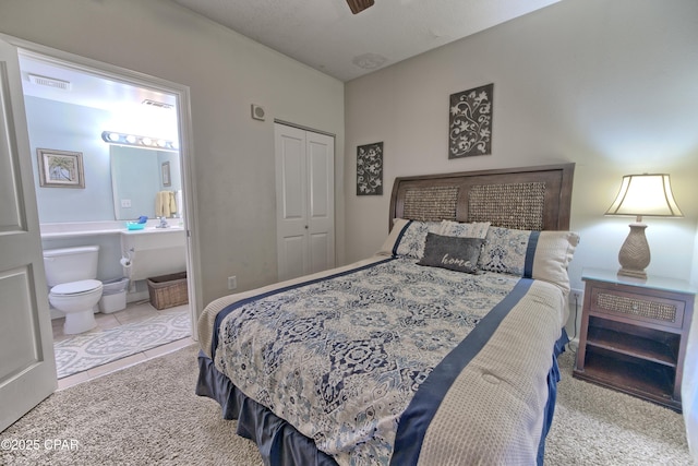 bedroom featuring tile patterned flooring, ensuite bath, visible vents, and a closet