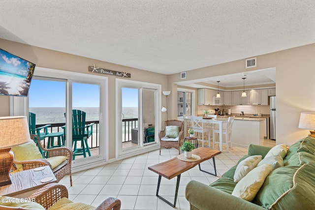 living area featuring visible vents, a textured ceiling, and light tile patterned floors