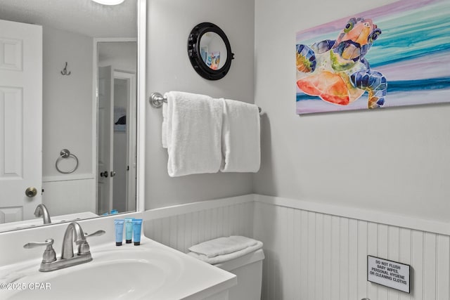 bathroom with wainscoting, a sink, and toilet