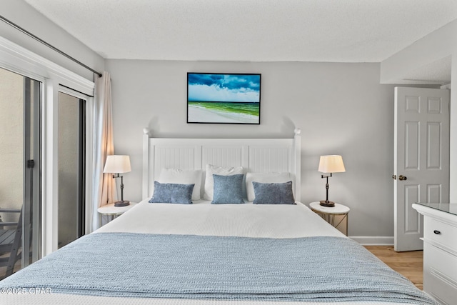 bedroom featuring light wood-style flooring, baseboards, and a textured ceiling