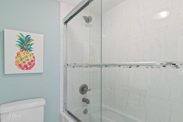 bathroom featuring shower / bath combination with glass door and toilet