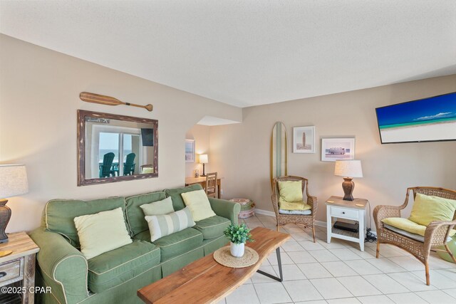 living room with light tile patterned floors, baseboards, and arched walkways