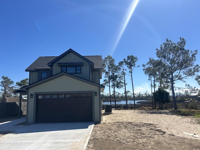 view of front of home featuring a water view, fence, board and batten siding, concrete driveway, and central AC unit