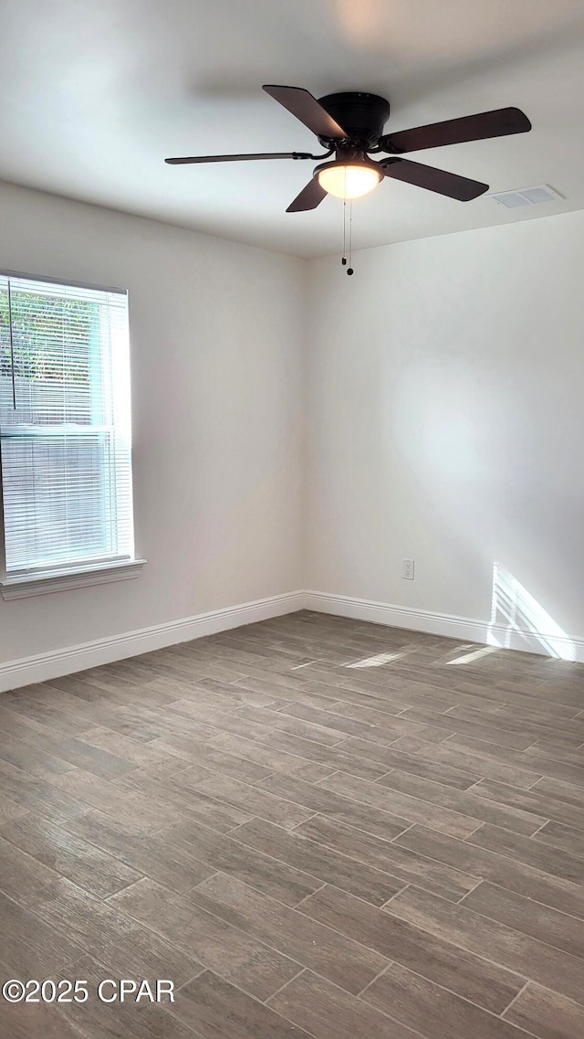 spare room with visible vents, wood finished floors, baseboards, and ceiling fan