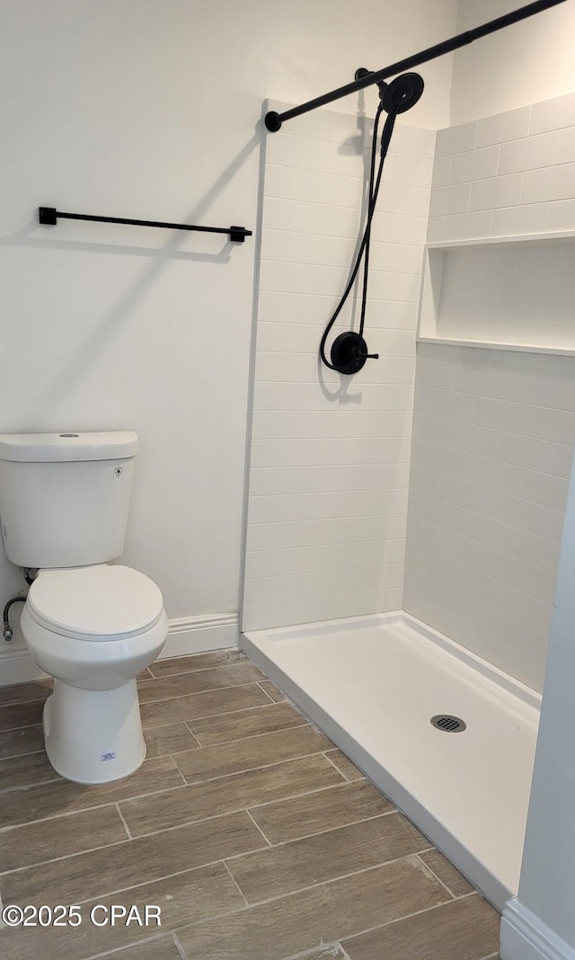 full bath with baseboards, toilet, a shower stall, and wood tiled floor