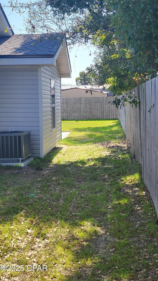 view of yard with central AC unit and a fenced backyard