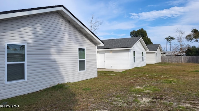 view of property exterior featuring a yard, fence, and a shingled roof