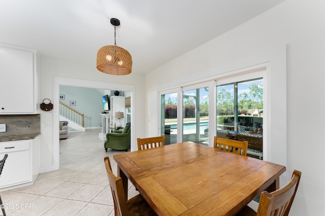 dining area featuring light tile patterned floors, baseboards, and stairs