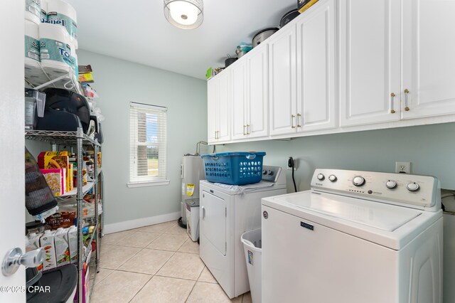 laundry area featuring light tile patterned floors, cabinet space, independent washer and dryer, and baseboards