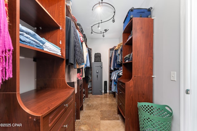 walk in closet featuring stone finish floor