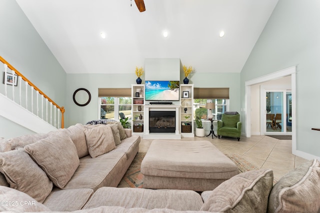 living area featuring high vaulted ceiling, stairway, tile patterned floors, and plenty of natural light