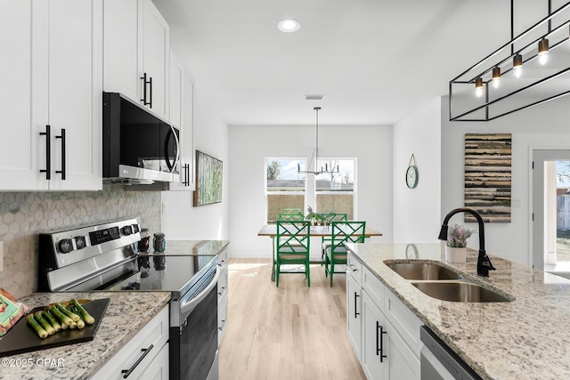 kitchen featuring a notable chandelier, a sink, appliances with stainless steel finishes, white cabinetry, and light wood finished floors