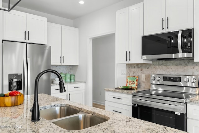 kitchen with decorative backsplash, a sink, white cabinets, and stainless steel appliances