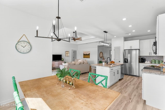 kitchen featuring an inviting chandelier, white cabinets, appliances with stainless steel finishes, a kitchen island with sink, and a sink