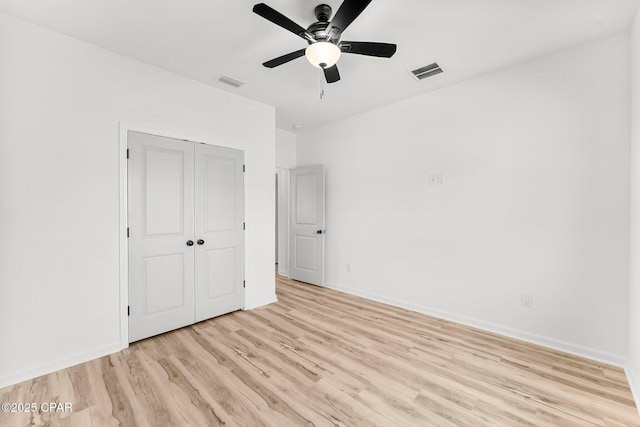 unfurnished bedroom with light wood-style floors, a closet, baseboards, and visible vents