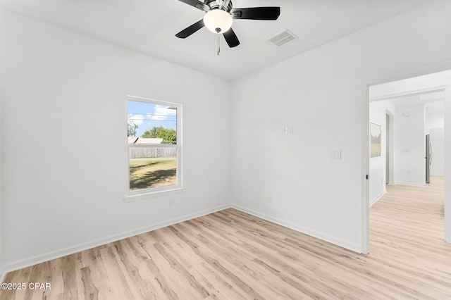 spare room with light wood-style floors, baseboards, a ceiling fan, and visible vents