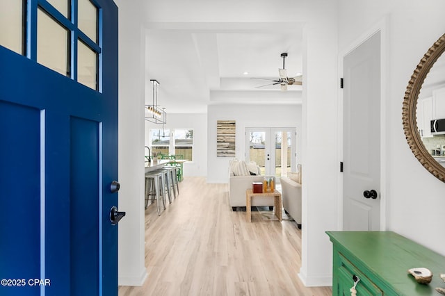 entrance foyer featuring light wood-style floors, a ceiling fan, recessed lighting, a raised ceiling, and french doors
