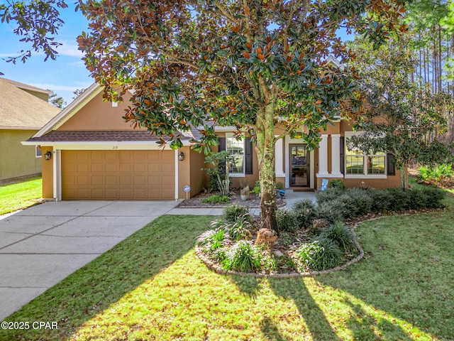 view of property hidden behind natural elements featuring driveway, an attached garage, a front yard, and stucco siding