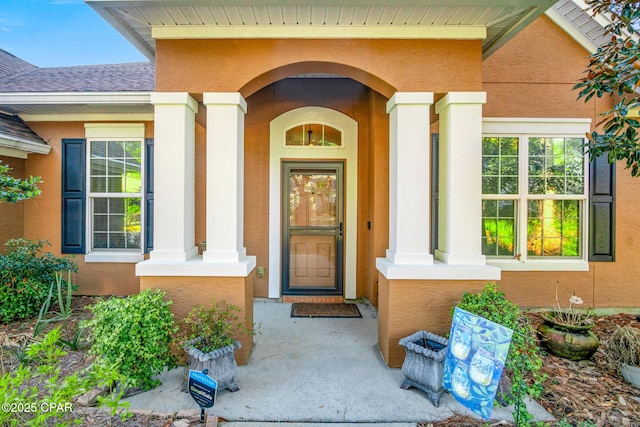 property entrance with a shingled roof and stucco siding