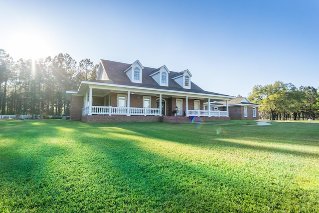 view of front of house featuring brick siding, covered porch, and a front lawn