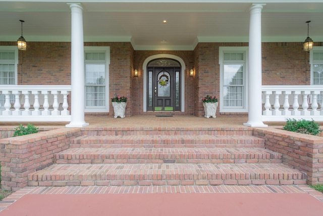 property entrance featuring brick siding and a porch